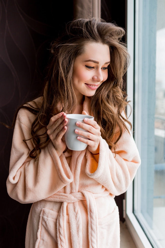 fresh-young-woman-pink-tender-bathrobe-drink-tea-looking-out-window